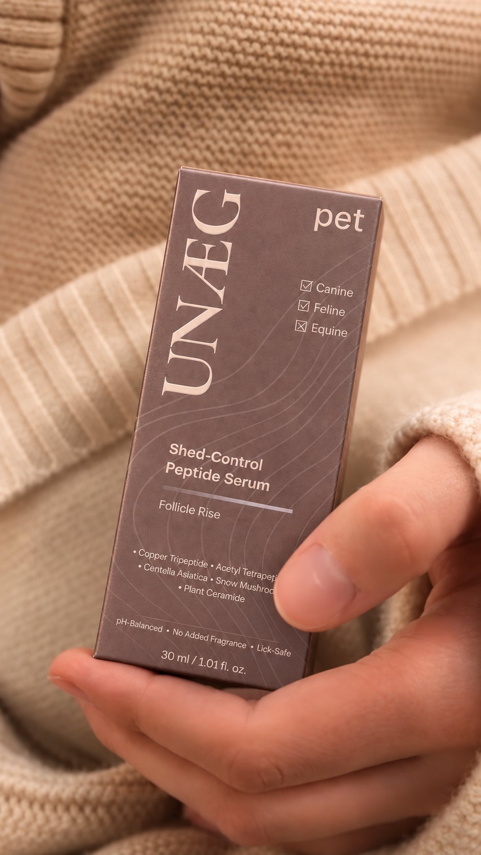 Hand holding the UNÆG Pet Shed-Control Peptide Serum (Follicle Rise) box, 30 ml, for canine and feline coats